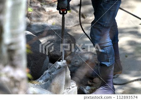 Chiseling work - crushing concrete blocks with a hammer drill 112893574