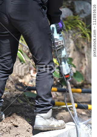 鑿工:工人用錘鑽切割混凝土塊 鑿工:工人用錘鑽切割混凝土塊 112893616