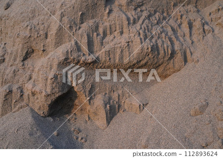 Sand dune texture close-up. Textured sand hill with volume shadows of sandy topography in the sunset. Beach, construction and gardening ingredient. 112893624