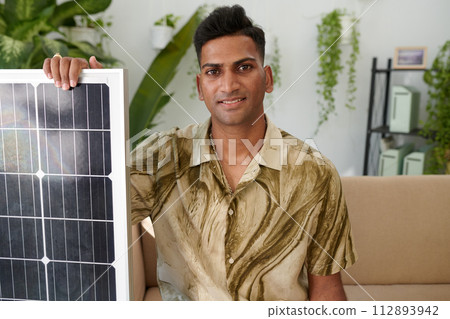 Portrait of smiling Indian man showing solar panel he ordered for his system 112893942