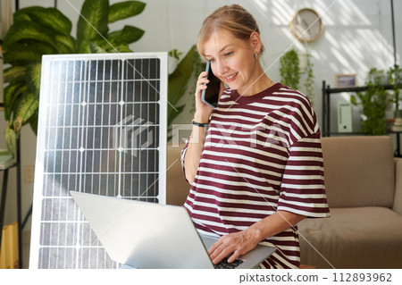 Smiling woman calling to client service to get information on how to change broken solar panel 112893962