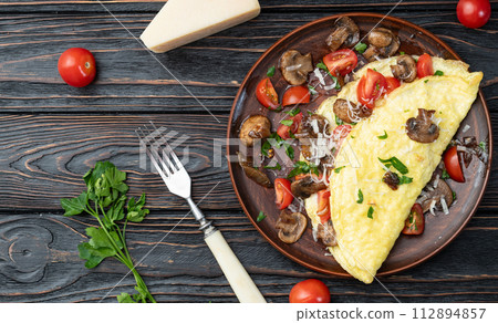 Omelette stuffed with mushrooms , tomatoes and parsley 112894857
