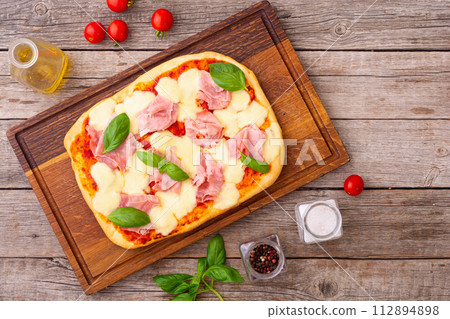 Traditional italian pizza with ham mozzarella and  basil 112894898