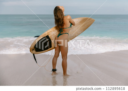 Surfgirl with surfboard goes to surfing. Surfer woman in sexy bikini on ocean beach Surfgirl with surfboard goes to surfing. Surfer woman in sexy bikini on ocean beach 112895618