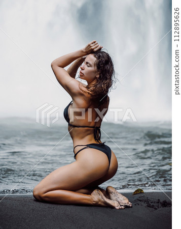 Gorgeous woman in bikini near powerful waterfall in Bali. 112895626