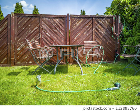 BBQ grillage rost and hose lying on the wet lawn BBQ grillage rost and hose lying on the wet lawn 112895760