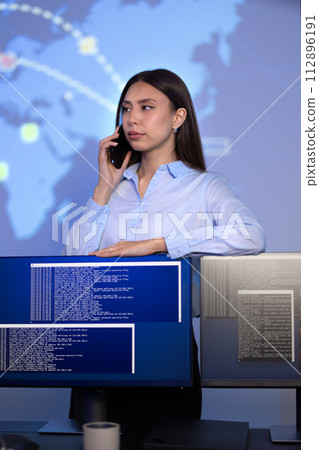 Focused Female Cybersecurity Manager talking in the phone in Enterprise Cyber Security Operations Center SOC 112896191