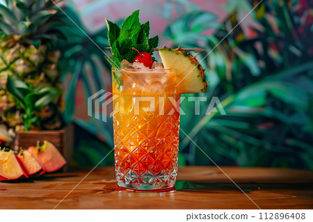 mai tai cocktail with pine apple and palm tree leaves on background 112896408