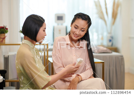 Waxing specialist showing cassette to client before procedure 112896454