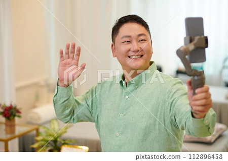 Smiling influencer filming review of wax salon for his blog 112896458