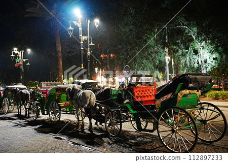 Horse-drawn carriages at Jemaa el-Fnaa in Marrakesh in Morocco at evening 112897233