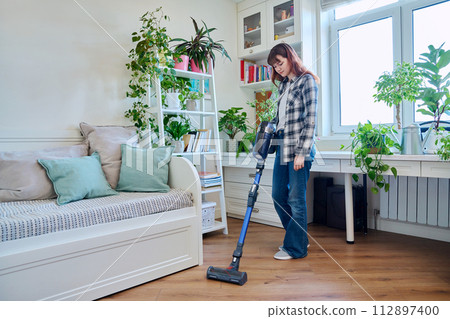 Young teenage female doing vacuuming at home 112897400