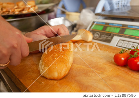 A man cuts bread for bruschetta against the background of electronic scales 112897590