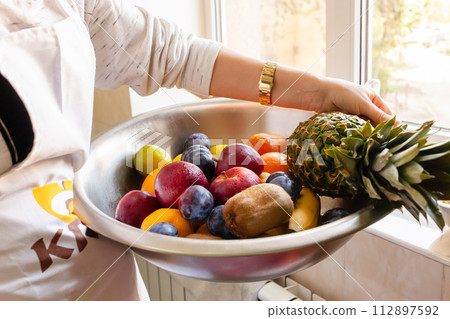 Fruits and vegetables in a large wash bowl. The pastry chef collects the fruit 112897592
