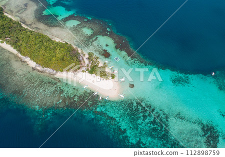 Aerial view of a tropical island with palm trees and white sand beaches. Amazing tropical island in the middle of the ocean. . Aerial view of a tropical island with palm trees and white sand beaches. Amazing tropical island in the middle of the ocean. . 112898759