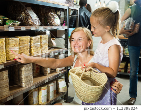Mother with daughter buy corn cakes in store Mother with daughter buy corn cakes in store 112898824