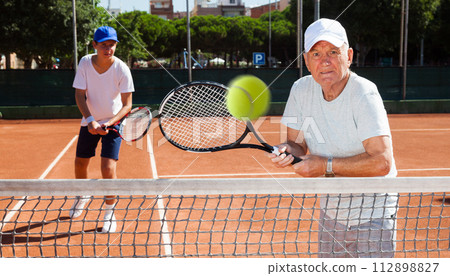Grandfather and grandson playing tennis court Grandfather and grandson playing tennis court 112898827