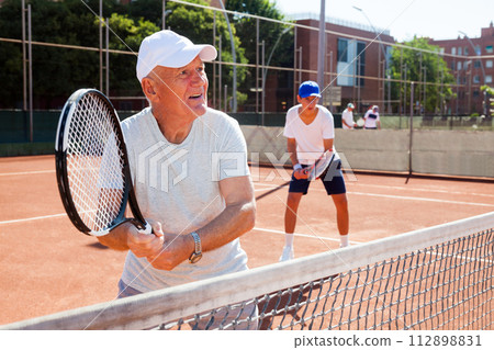 Grandfather and grandson playing tennis court Grandfather and grandson playing tennis court 112898831