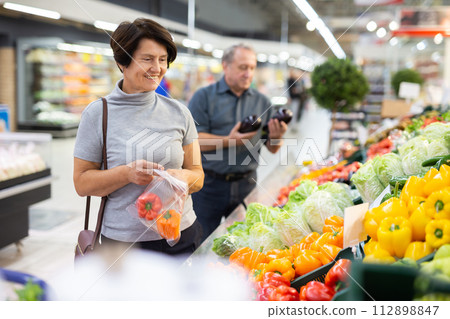 Elderly woman chooses pepper in vegetable and fruit department 112898847