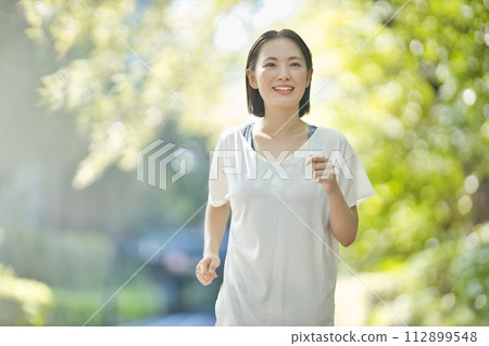 穿著運動服跑步的微笑的年輕女子 穿著運動服跑步的微笑的年輕女子 112899548