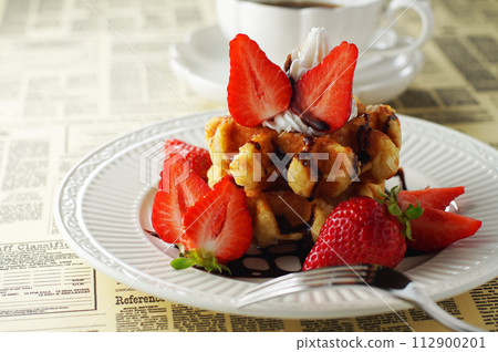 Belgian waffles and strawberries with chocolate sauce and coffee 112900201