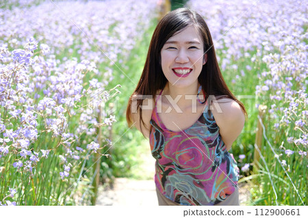 Beautiful Asian woman is smiling and relaxing in blooming purple Murdannia giganteum flowers field 112900661