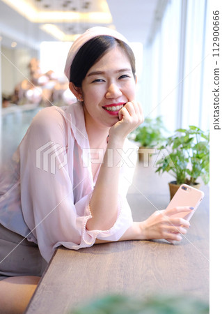Beautiful Asian businesswoman is smiling and relaxing in cafe Beautiful Asian businesswoman is smiling and relaxing in cafe 112900666