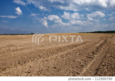 Clouds hover over a large expanse of tilled soil. Clouds hover over a large expanse of tilled soil. 112900790