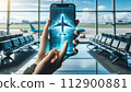 A hand holds a phone displaying a 3D airplane hologram, 112900881