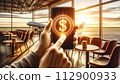 A hand holds a mobile phone with a simple 3D dollar coin hologram floating outside 112900933