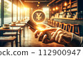 a hand holds a phone with a floating 3D yen coin hologram 112900947