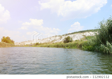 Ancient multimillion chalk mountains on the steppe surface of earth. White chalk mountains in landscape with river and green trees Ancient multimillion chalk mountains on the steppe surface of earth. White chalk mountains in landscape with river and green trees 112902112