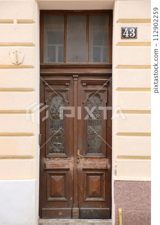 Old ancient wooden door texture in european medieval style. The detailed texture of closed brown aged door from weathered and stained wooden planks and boards Old ancient wooden door texture in european medieval style. The detailed texture of closed brown aged door from weathered and stained wooden planks and boards 112902259