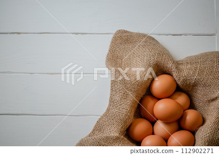 Fresh chicken eggs in a basket on a sack, egg day, wooden table.Selective focus 112902271