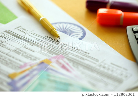 Indian income tax return blank form with pen and indian rupees bills on indian country flag close up. Annual tax report concept 112902301