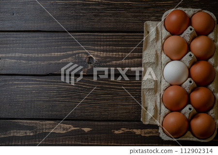 Fresh chicken eggs in a paper tray on the table, selective focus 112902314