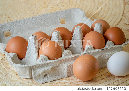 Fresh chicken eggs in a paper tray on the table, selective focus 112902320
