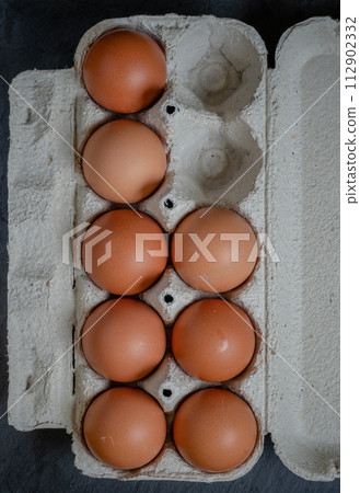 Fresh chicken eggs in a paper tray on the table, selective focus 112902332