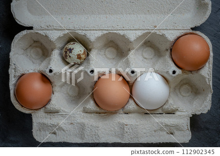 Fresh quail and chicken eggs in a paper tray, top view selective focus 112902345