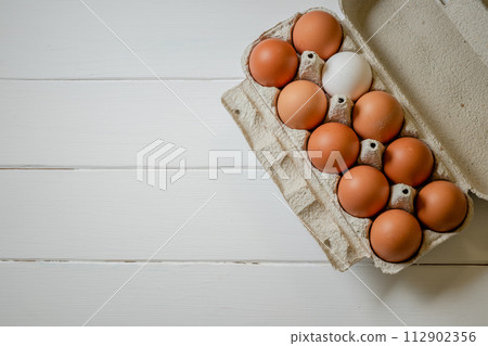 Fresh chicken eggs in a paper tray on the table, selective focus 112902356