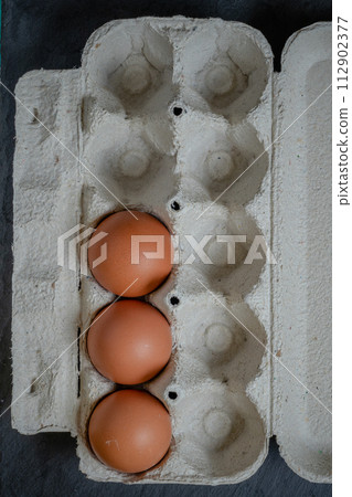 Fresh chicken eggs in a paper tray on the table, selective focus Fresh chicken eggs in a paper tray on the table, selective focus 112902377