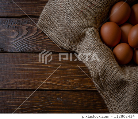 Fresh chicken eggs in a basket on a sack, egg day, wooden table.Selective focus 112902434