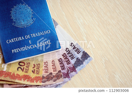 Brazilian work card and social security blue book and reais money bills close up Brazilian work card and social security blue book and reais money bills close up 112903006