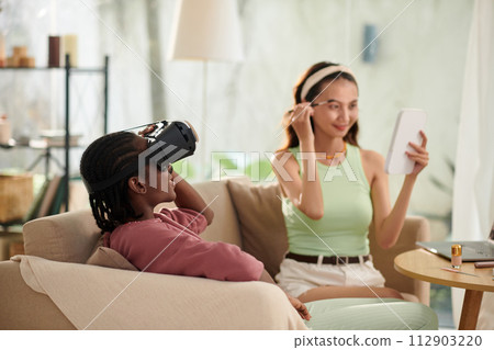 Black girl playing videogame when her friend doing makeup 112903220