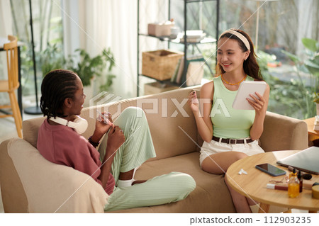 Cheerful diverse friends doing manicure and makeup at home Cheerful diverse friends doing manicure and makeup at home 112903235