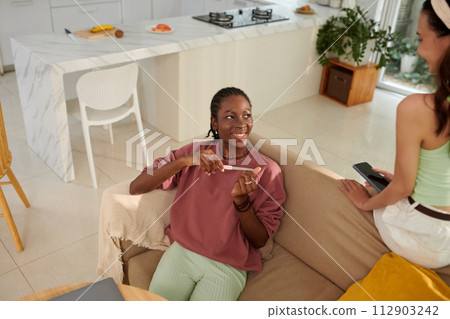 Smiling teenage girl filing nails and talking to roommate Smiling teenage girl filing nails and talking to roommate 112903242