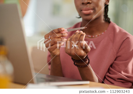 Closeup image of teenage Black girl filing nails 112903243