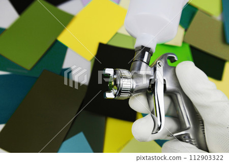 paint spray gun at work at the workplace in the workshop, selection of tools, paint samples 112903322