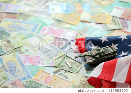 Tank on United States flag on many banknotes of different currency. Background of war funding and military support price for United States of America Tank on United States flag on many banknotes of different currency. Background of war funding and military support price for United States of America 112903365