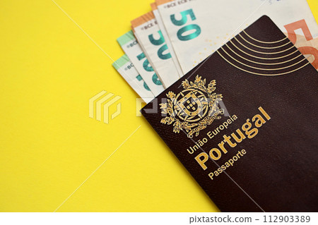 Red Portugal passport of European Union and money on yellow background close up. Tourism and citizenship concept Red Portugal passport of European Union and money on yellow background close up. Tourism and citizenship concept 112903389